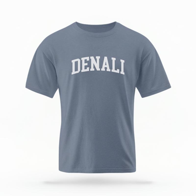 The Blue Jean Unisex Denali Alaska Varsity T-shirt is set against a Ghost - White Studio background. The Denali Alaska Varsity graphic is in a Varsity style.