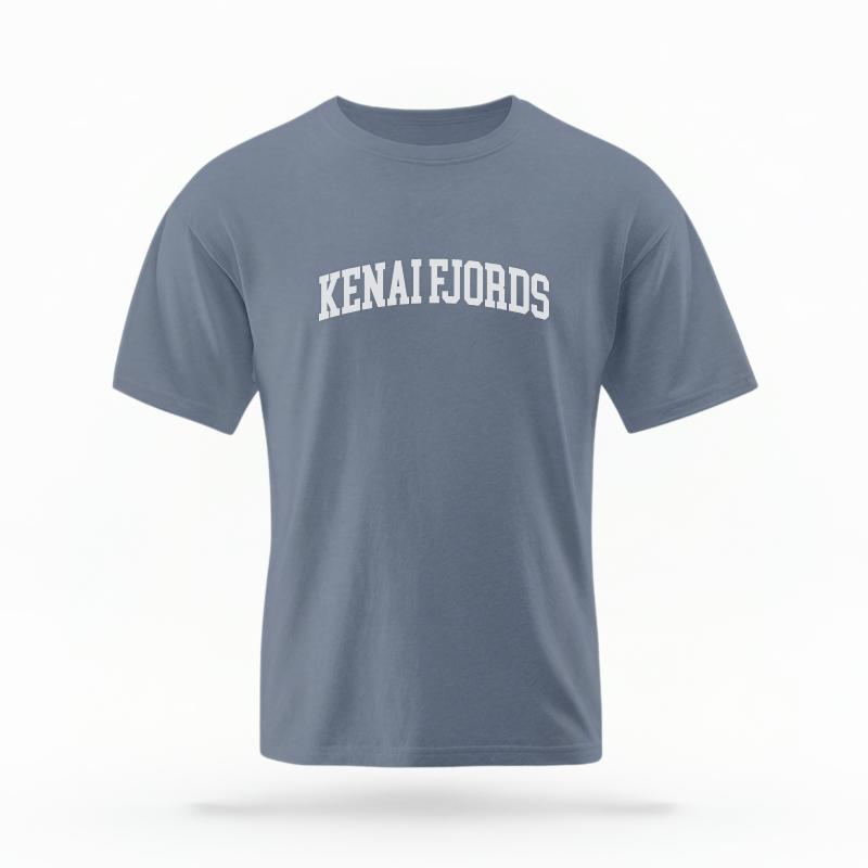 The Blue Jean Unisex Kenai Fjords Alaska Varsity T-shirt is set against a Ghost - White Studio background. The Kenai Fjords Alaska Varsity graphic is in a Varsity style.