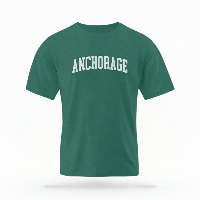 The Blue Spruce Unisex Anchorage Alaska Varsity T-shirt is set against a Ghost - White Studio background. The Anchorage Alaska Varsity graphic is in a Varsity style.