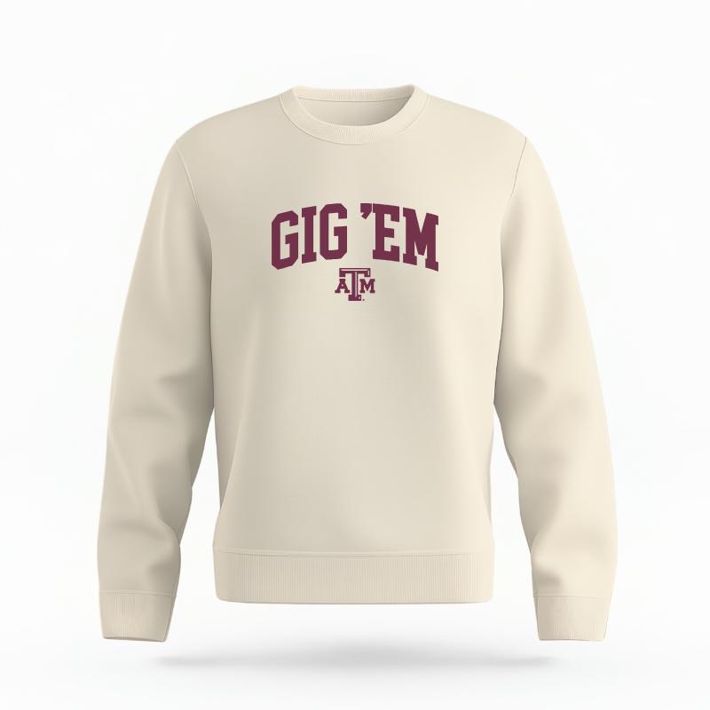 The Ivory Unisex Gig 'Em Varsity Organic Cotton Crewneck is set against a Ghost - White Studio background. The Gig 'Em Varsity graphic is in a Sports Graphics style.