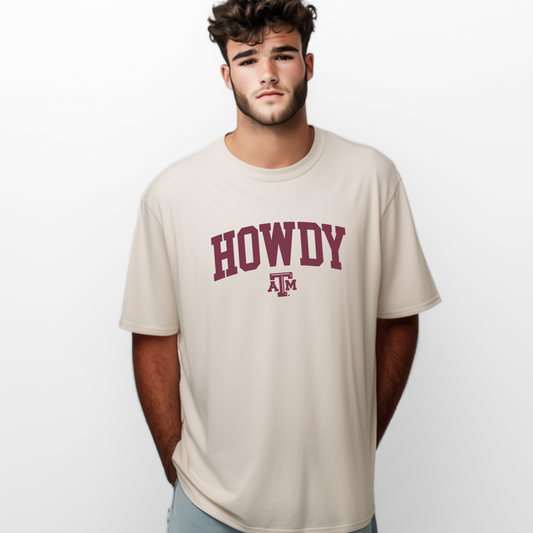 The Ivory Unisex Howdy Varsity T-shirt is worn by a model. The Howdy Varsity graphic is in a Varsity style.