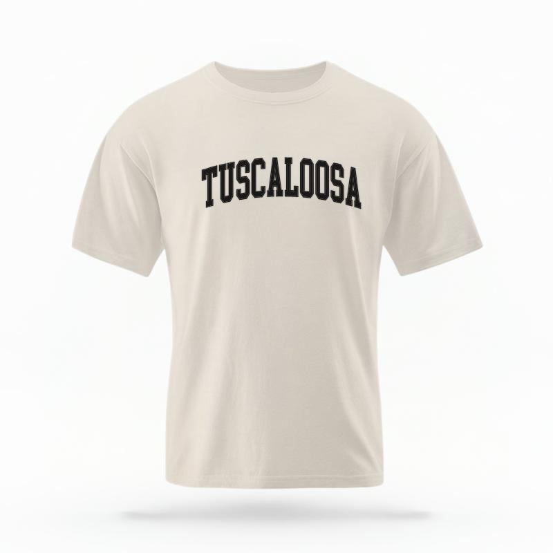 The Ivory Unisex Tuscaloosa Varsity T-shirt is set against a Ghost - White Studio background. The Tuscaloosa Varsity graphic is in a Varsity style.