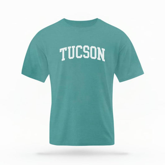 The Seafoam Unisex Tucson AZ Varsity T-shirt is set against a Ghost - White Studio background. The Tucson AZ Varsity graphic is in a Varsity style.