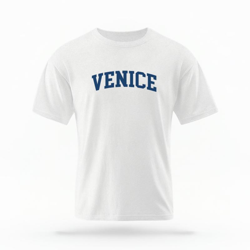 The White Unisex Venice CA Varsity T-shirt is set against a Ghost - White Studio background. The Venice CA Varsity graphic is in a Varsity style.