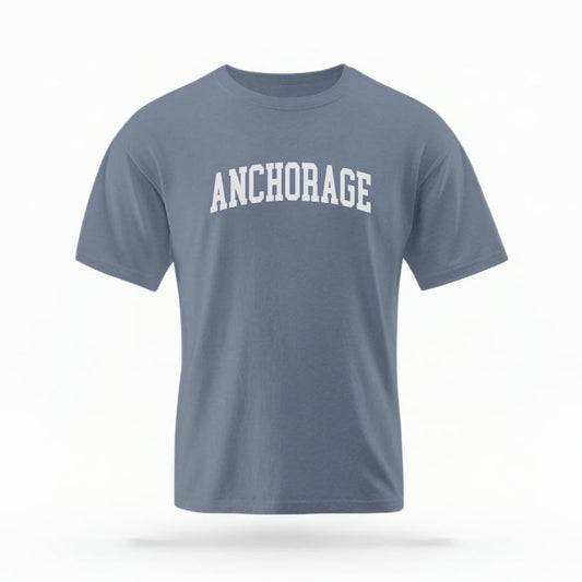 The Blue Jean Unisex Anchorage Alaska Varsity T-shirt is set against a Ghost - White Studio background.  The Anchorage Alaska Varsity graphic is in a Varsity style. 