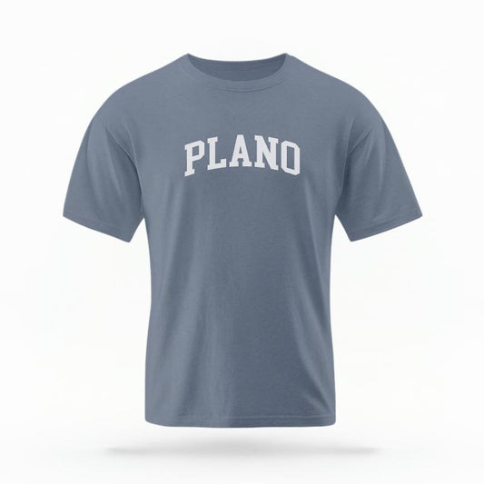 The Blue Jean Unisex Plano Texas Varsity T-shirt is set against a Ghost - White Studio background.  The Plano Texas Varsity graphic is in a Varsity style. 