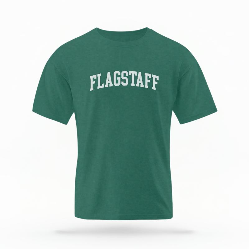The Blue Spruce Unisex Flagstaff AZ Varsity T-shirt is set against a Ghost - White Studio background.  The Flagstaff AZ Varsity graphic is in a Varsity style. 