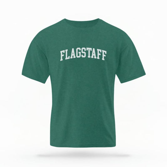 The Blue Spruce Unisex Flagstaff AZ Varsity T-shirt is set against a Ghost - White Studio background.  The Flagstaff AZ Varsity graphic is in a Varsity style. 