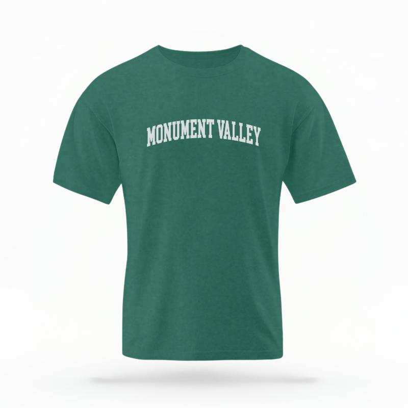 The Blue Spruce Unisex Monument Valley AZ Varsity T-shirt is set against a Ghost - White Studio background.  The Monument Valley AZ Varsity graphic is in a Varsity style. 