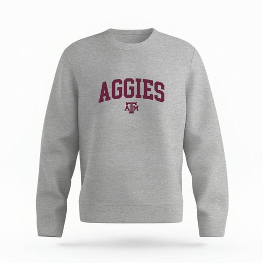 The Heather Grey Unisex Aggies Varsity Organic Cotton Crewneck is set against a Ghost - White Studio background.  The Aggies Varsity graphic is in a Sports Graphics style. 