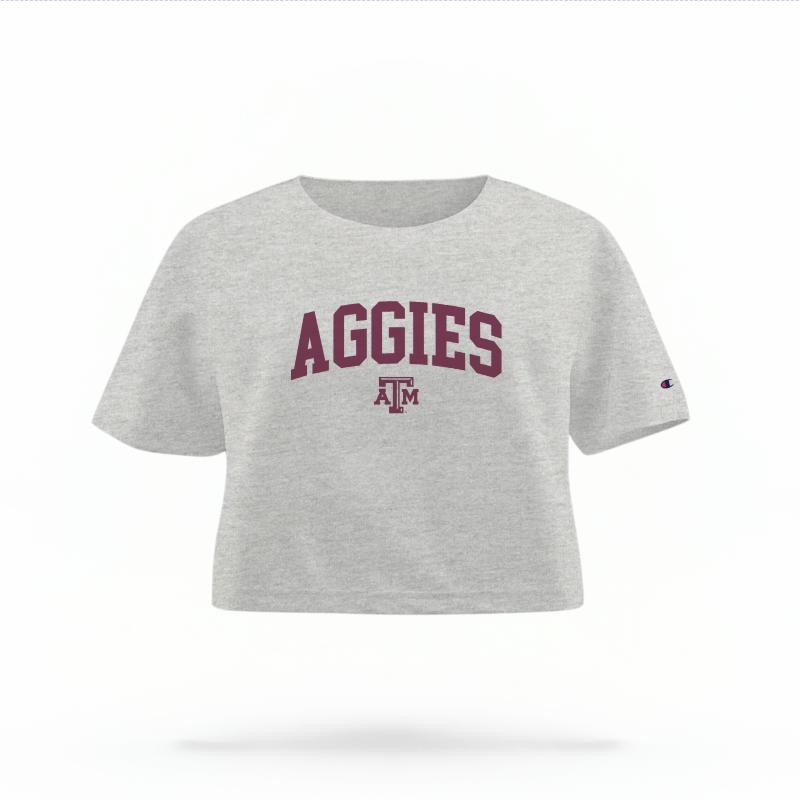 The Heather Grey Female Aggies Varsity Women's Boxy Crop Top is set against a Ghost - White Studio background.  The Aggies Varsity graphic is in a Sports Graphics style. 