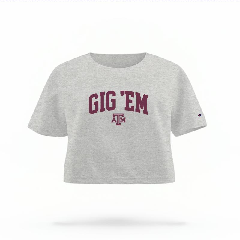 The Heather Grey Female Gig 'Em Varsity Women's Boxy Crop Top is set against a Ghost - White Studio background.  The Gig 'Em Varsity graphic is in a Sports Graphics style. 