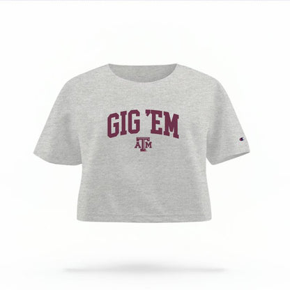 The Heather Grey Female Gig 'Em Varsity Women's Boxy Crop Top is set against a Ghost - White Studio background.  The Gig 'Em Varsity graphic is in a Sports Graphics style. 