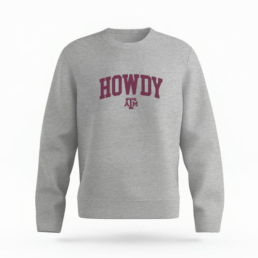 The Heather Grey Unisex Howdy Varsity Organic Cotton Crewneck is set against a Ghost - White Studio background.  The Howdy Varsity graphic is in a Sports Graphics style. 