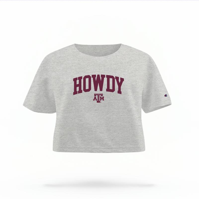 The Heather Grey Female Howdy Varsity Women's Boxy Crop Top is set against a Ghost - White Studio background.  The Howdy Varsity graphic is in a Sports Graphics style. 