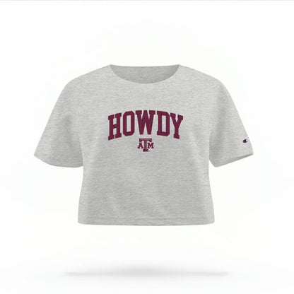 The Heather Grey Female Howdy Varsity Women's Boxy Crop Top is set against a Ghost - White Studio background.  The Howdy Varsity graphic is in a Sports Graphics style. 