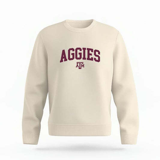 The Ivory Unisex Aggies Varsity Organic Cotton Crewneck is set against a Ghost - White Studio background.  The Aggies Varsity graphic is in a Sports Graphics style. 