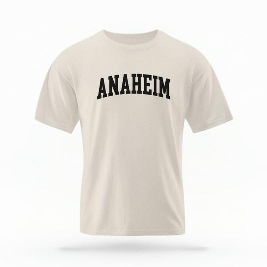 The Ivory Unisex Anaheim CA Varsity T-shirt is set against a Ghost - White Studio background.  The Anaheim CA Varsity graphic is in a Varsity style. 