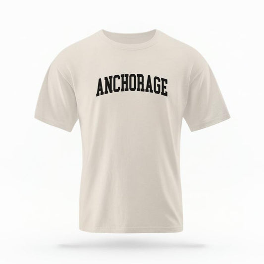 The Ivory Unisex Anchorage Alaska Varsity T-shirt is set against a Ghost - White Studio background.  The Anchorage Alaska Varsity graphic is in a Varsity style. 