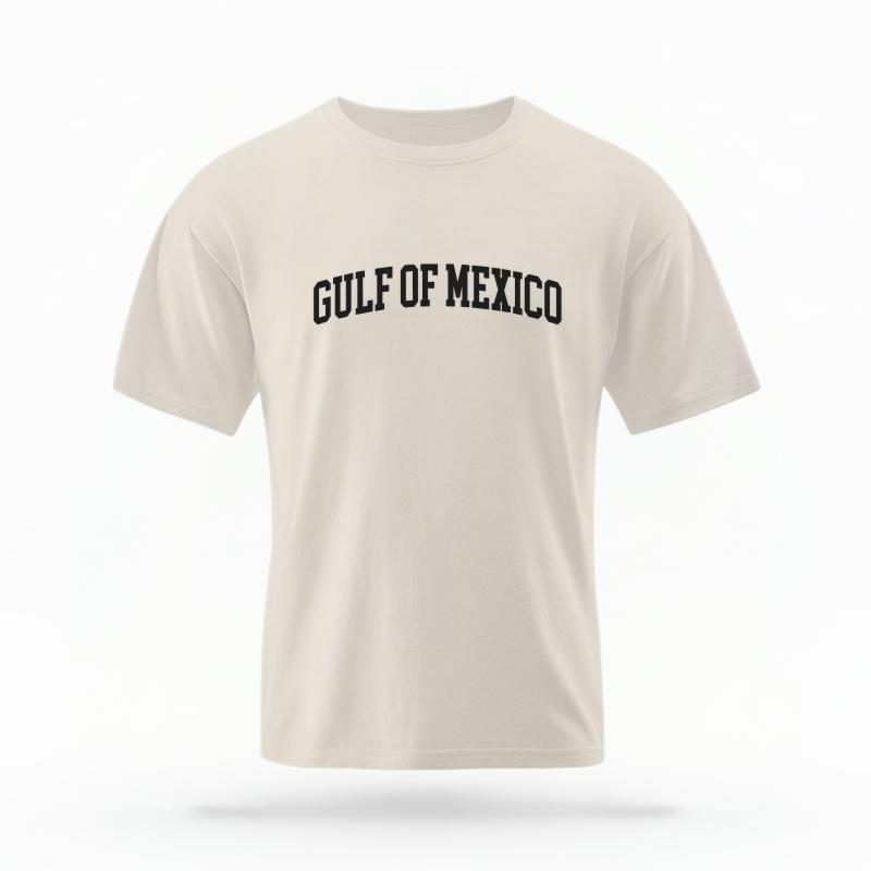 The Ivory Unisex Gulf of Mexico Varsity T-shirt is set against a Ghost - White Studio background.  The Gulf of Mexico Varsity graphic is in a Varsity style. 