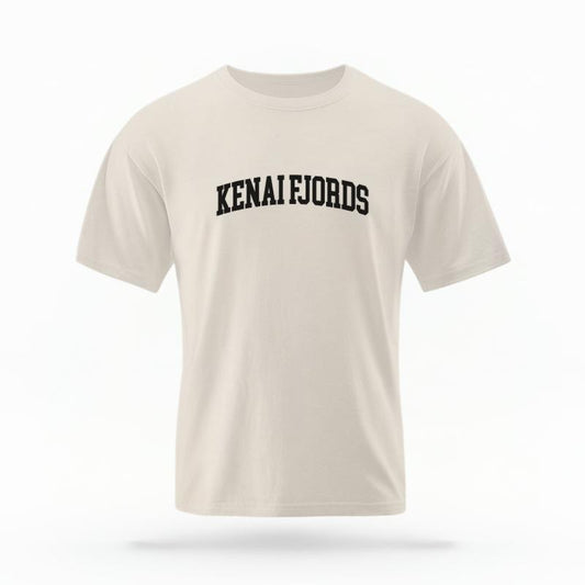 The Ivory Unisex Kenai Fjords Alaska Varsity T-shirt is set against a Ghost - White Studio background.  The Kenai Fjords Alaska Varsity graphic is in a Varsity style. 
