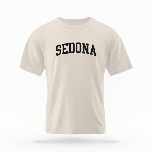 The Ivory Unisex Sedona AZ Varsity T-shirt is set against a Ghost - White Studio background.  The Sedona AZ Varsity graphic is in a Varsity style. 