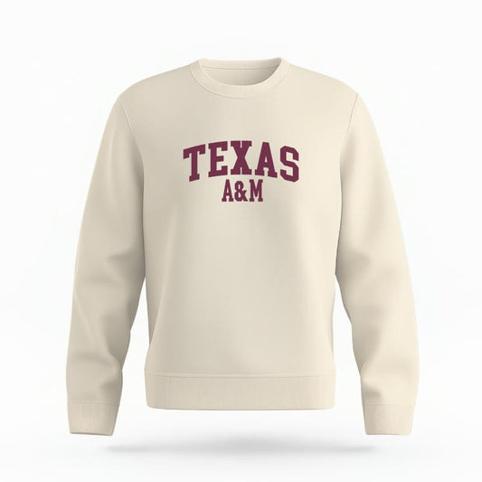 The Ivory Unisex Texas A&M Varsity Organic Cotton Crewneck is set against a Ghost - White Studio background.  The Texas A&M Varsity graphic is in a Sports Graphics style. 