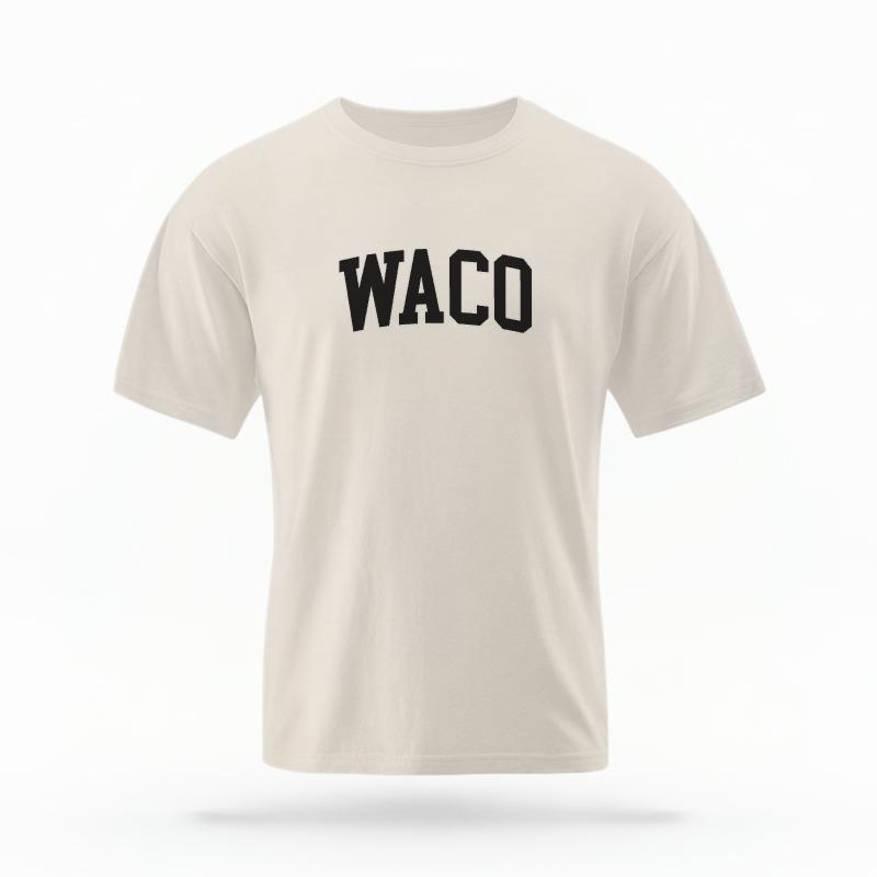 The Ivory Unisex Waco Varsity T-shirt is set against a Ghost - White Studio background.  The Waco Varsity graphic is in a Varsity style. 