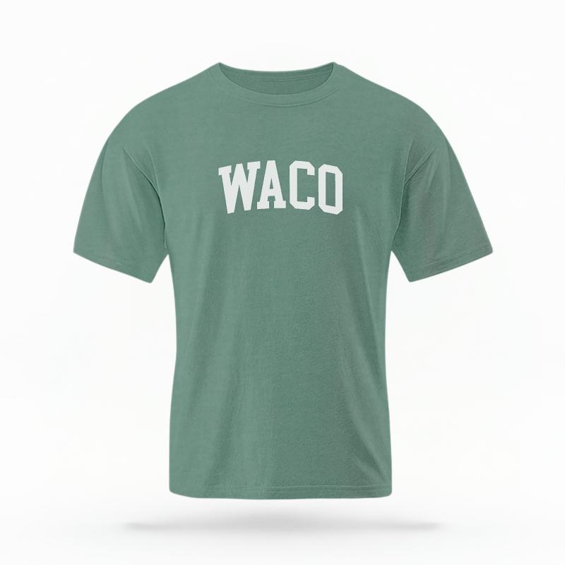 The Light Green Unisex Waco Varsity T-shirt is set against a Ghost - White Studio background.  The Waco Varsity graphic is in a Varsity style. 