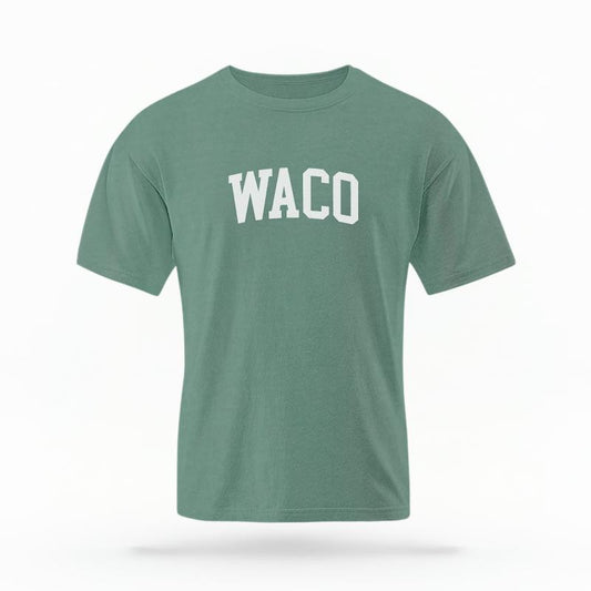 The Light Green Unisex Waco Varsity T-shirt is set against a Ghost - White Studio background.  The Waco Varsity graphic is in a Varsity style. 
