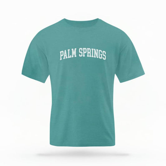 The Seafoam Unisex Palm Springs CA Varsity T-shirt is set against a Ghost - White Studio background.  The Palm Springs CA Varsity graphic is in a Varsity style. 