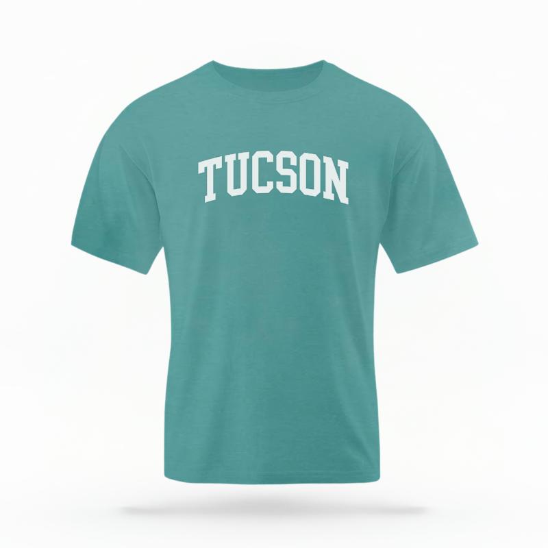 The Seafoam Unisex Tucson AZ Varsity T-shirt is set against a Ghost - White Studio background.  The Tucson AZ Varsity graphic is in a Varsity style. 