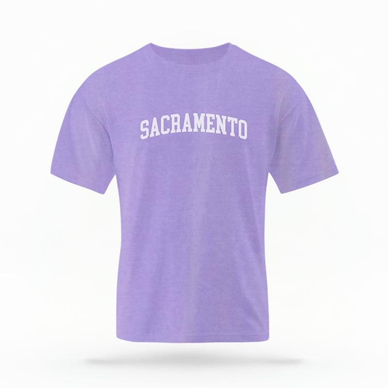 The Violet Unisex Sacramento CA Varsity T-shirt is set against a Ghost - White Studio background.  The Sacramento CA Varsity graphic is in a Varsity style. 