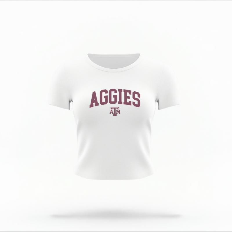 The White Female Aggies Varsity Women's Baby Tee is set against a Ghost - White Studio background.  The Aggies Varsity graphic is in a Varsity style. 