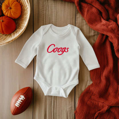 The White Unisex Coogs Script Infant Long Sleeve Bodysuit is set against a lifestyle background.  The Coogs Script graphic is in a Sports Graphics style. 