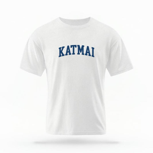 The White Unisex Katmai Alaska Varsity T-shirt is set against a Ghost - White Studio background.  The Katmai Alaska Varsity graphic is in a Varsity style. 
