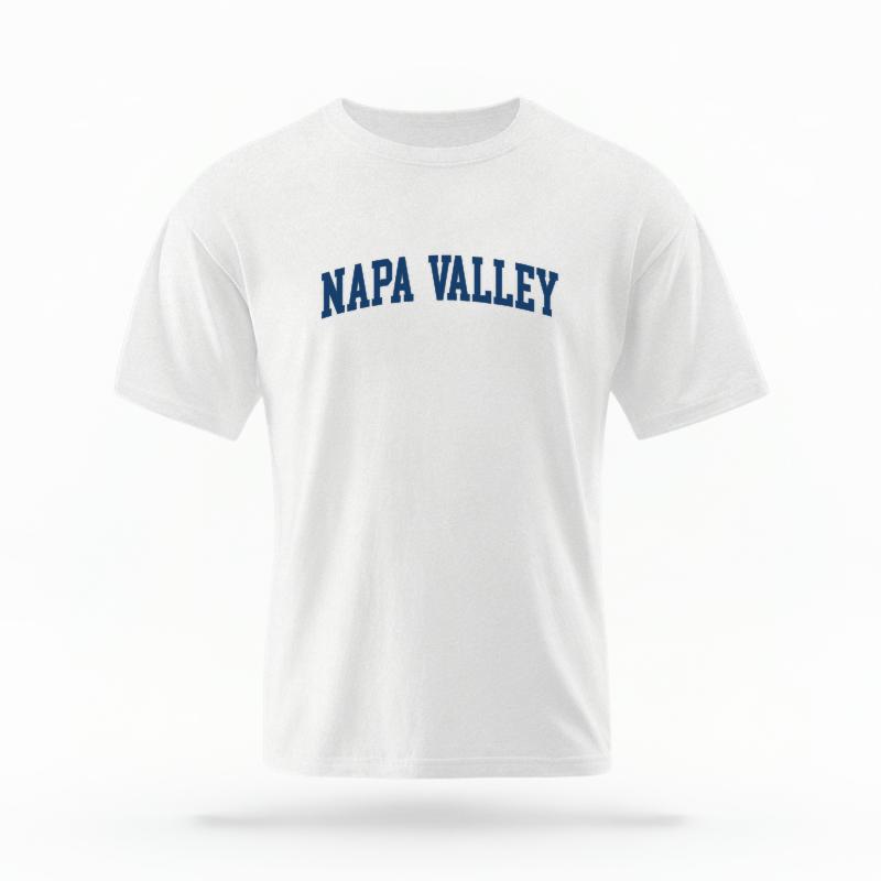 The White Unisex Napa Valley CA Varsity T-shirt is set against a Ghost - White Studio background.  The Napa Valley CA Varsity graphic is in a Varsity style. 