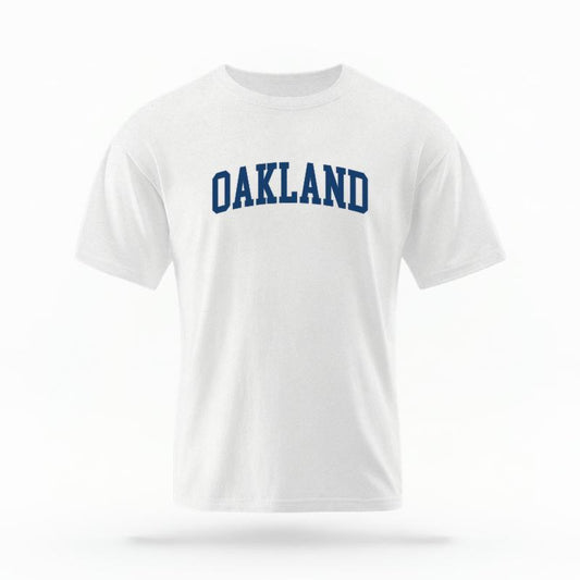 The White Unisex Oakland CA Varsity T-shirt is set against a Ghost - White Studio background.  The Oakland CA Varsity graphic is in a Varsity style. 