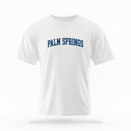 The White Unisex Palm Springs CA Varsity T-shirt is set against a Ghost - White Studio background.  The Palm Springs CA Varsity graphic is in a Varsity style. 